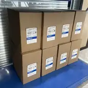 Row of 3G3MX2-AB015-V2 shipping cartons on warehouse shelving showing the same Omron Corporation cartridge label repeated on each box