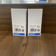 Omron C500-CE404 — two C500-CE404 boxes side by side on a wooden surface with the C500-CE404 type label, lot number 03325K, and barcode on the front of each white box
