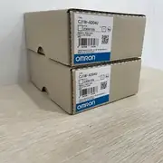 Omron CJ1W-AD04U — top label close-up showing the part number, the universal input range marking, the 1/8000 resolution rating, and the CJ-series backplane connector on the underside
