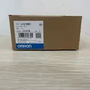 Omron CJ1W-DRM21 mounted in a CJ2M PLC rack with DeviceNet thick cable connected to the 5-pin connector — wired to a network of 8 DRT2-MD16S remote I/O blocks on a packaging line, with the NS (network status) LED showing solid green for healthy bus operation