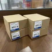 Omron CJ1W-EIP21 — brown Omron-branded cardboard shipping carton with the CJ1W-EIP21 type label, the EtherNet/IP Unit subtext, the Ver. 1.0 subtext, the KCC-REM-OMR-CJ1W-00032 KC mark, the lot number 231015M, the barcode, and the blue-and-white OMRON band along the bottom