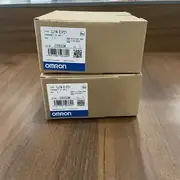 Omron CJ1W-EIP21 — second angle of the brown Omron-branded shipping carton showing the side panel with the CJ1W-EIP21 type label, the Ver. 1.0 subtext, the KCC-REM-OMR-CJ1W-00032 KC mark, the lot number 231015M, and the blue-and-white OMRON band