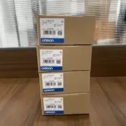 Omron CJ1W-EIP21 — third angle of the brown Omron-branded shipping carton with the CJ1W-EIP21 type label, the KCC-REM-OMR-CJ1W-00032 KC mark, and the blue-and-white OMRON band, photographed against a white background