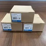 Omron CJ1W-ETN21 — stack of three brown Omron shipping cartons on a wooden surface, each showing the TYPE CJ1W-ETN21 ETHERNET UNIT label, KCC mark, lot 230819M, and blue-and-white OMRON band
