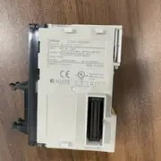 Hand holding the CJ1W-MD232 box to show the slim 31 mm-wide module carton size from another angle