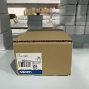 Omron CJ1W-PA202 mounted as the leftmost unit on a CJ-series rack with a CJ2M CPU and several CJ1W I/O units - the slim 45 mm width visible against the wider I/O modules