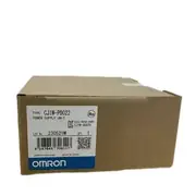 Omron CJ1W-PD022 — brown cardboard box with the CJ1W-PD022 type label, KCC-REM-OMR-CJ1W-00029 cert, lot 230521M, barcode, and the OMRON Corporation wordmark with the blue/white OMRON band at the bottom