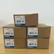 Omron CJ1W-PD022 — stack of five brown cardboard boxes (one on top, four in a 2x2 grid) each with the same CJ1W-PD022 type label, KCC-REM-OMR-CJ1W-00029 cert, lot 230521M, and the blue/white OMRON band at the bottom