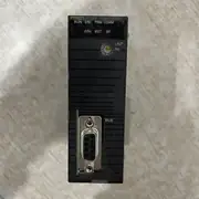 Omron CJ1W-PRM21 — front face of the CJ1W-PRM21 module on a wooden surface showing the green PRM21 LED indicator at top / black RUN ERC PRM COMM ERH BST BF LED array / UNIT No. 0-9 / A-F rotary selector / D-Sub 9-pin PROFIBUS BUS connector on the lower housing with the BUS label to its right