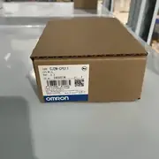 Omron CJ2M-CPU11 mounted in a CJ2M rack with CJ1W-PA202 power supply + CJ1W-ID211 input + CJ1W-OD212 output on a small packaging machine - the USB cable connects to a laptop running CX-Programmer for programming and the RS-232C port connects to an NB5Q HMI via NT Link