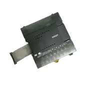 Omron CP1W-DA021 — top view of the CP1W module showing the white DA021 label, the printed terminal markings CH / OUT / VOUT1 VOUT2 COM1 COM2 with NC pin labels for the unused terminals, and the 16-pin grey flat expansion cable exiting the left-hand side