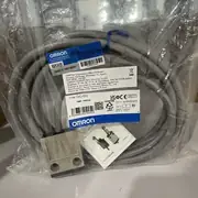 Omron D4C-1201 limit switch — sealed plastic bag with the metallic limit switch body visible (pin plunger on top, two mounting holes on the front), 3 m VCTF cable coiled, instruction sheet, and Omron label TYPE D4C-1201 LIMIT SWITCH, OMRON Corporation, MADE IN JAPAN, QTY 1, LOT No. 05325Z5