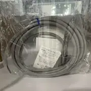 Omron D4C-1201 limit switch — close-up of the coiled 3 m cable inside the sealed plastic bag with Japanese instruction sheet showing dimensions drawing and usage notes