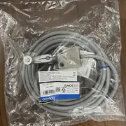 Omron D4C-1220 slim limit switch — installed at the end-of-stroke position on a pneumatic cylinder on a packaging machine; the 3 m cable routes back to the PLC cabinet, NC contact switches the 24 VDC solenoid valve directly