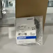 Omron E2E-X3D1-U — front view of the M12 shielded barrel showing the PBT sensing face, the operation indicator LED, and the pre-wired 2 m PVC cable trailing from the back