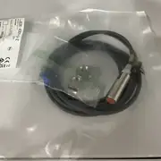 Omron E2E-X3D1-U — rear face with the two non-polarity 2-wire leads, the cable strain relief, and the operation indicator window on the back