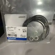 Omron E2E-X3D1-U installed flush in a metal bracket with the cable landed in a junction box and an iron target approaching the sensing face