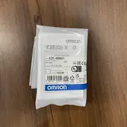 Omron E2E-X8MD1 2M M12 inductive sensor — top label close-up showing the model number E2E-X8MD1, the 8 mm sensing distance marking, the DC 2-wire polarized indicator, and the IP67 / CE / cULus certification marks