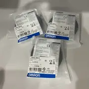 Omron E3FA-DN12 — single anti-static clear plastic bag of the sensor on a white plastic shelf with the E3FA-DN12 PHOTOELECTRIC SENSOR / 2m / 10 to 30V DC / LOT No. 01825M / QTY 1 type label, barcode 4 548583 312326, KCC-REM-OMR-CP1W-0013 KC mark, blue OMRON band at the bottom, with the General Compliance Information and Instructions for EU compliance print visible at the top of the bag
