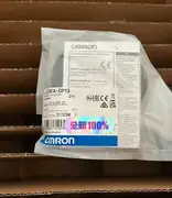 Omron E3FA-DP13 installed in a feeder bracket aimed at a small part on a 1 m wide conveyor, with an M12 patch cord trailing to the panel