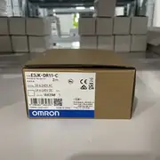 Omron E3JK-DR11-C — installed on the supplied E39-L40 right-angle bracket above a conveyor trigger point with the red aiming spot visible on a passing cardboard box