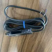 Omron E3X-HD41 1-channel fiber amplifier — installed in a DIN-rail cabinet with an E32-T11L 2 m through-beam fiber optic cable pair detecting label-edges on a labelling machine