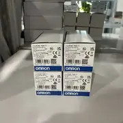 Omron E3X-NA11 2M digital fiber amplifier - side view showing the fiber-optic connector (E3X-CN type) on the front face accepting any E32-series fiber cable, and the 2 m pre-wired oil-resistant PVC cable (brown Vcc, blue 0V, black output, white mode select)