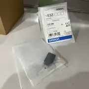 Omron E3Z-B86 installed above a conveyor with the E39-R1S reflector opposite and a clear PET bottle passing through the beam