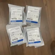 Four sealed Omron E3Z-D62 retail bags on a wooden surface, each showing the same E3Z-D62 product label, 12 to 24V DC rating, and the blue Omron logo