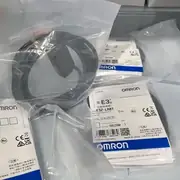 Omron E3Z-LR81 mounted beside an E39-R1 reflector across a packaging conveyor, triggering reliably on a foil-wrapped carton
