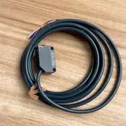 Omron E3Z-LS61 — small black ABS rectangular BGS photo sensor with OMRON wordmark and a 2 m oil-resistant cable coiled beside it on a wooden surface