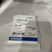 Omron E3Z-LS66 — front face of the E3Z rectangular housing showing the red 680 nm LED emitter window, the receiver lens, and the orange operation LED indicator on the top of the case