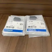 Omron E3Z-R86 installed opposite an E39-R1S reflector on a packaging conveyor with a shiny metal panel passing through the beam