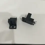 Omron EE-SX674 slot photomicrosensor — top view showing the T-shaped body with the 5 mm sensing slot running across the middle, two M3 mounting holes on the sides, and the EE-1006 4-pin connector plugged into the rear pins