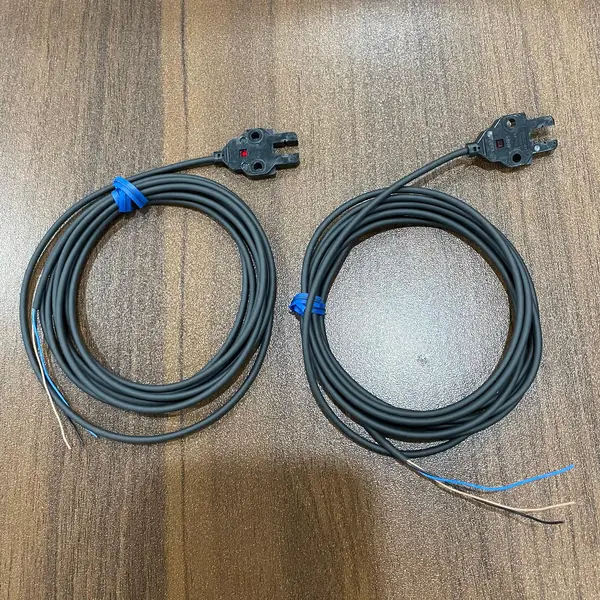 Omron EE-SX870 slim-cable slot photomicrosensor — front view showing the compact standard-body plastic housing (15 × 7.5 × 28 mm) with the 5 mm slot opening on the front face and the red operation indicator LED on the top
