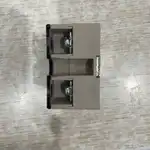 Omron G3NA-D210B-UTU DC5-24 solid state relay — top-down view showing the hockey-puck style gray plastic housing with two screw-mounting holes at the top and bottom and a transparent centre cover over the output terminals