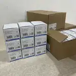 Omron G3NA-D210B-UTU DC5-24 solid state relay — eight stacked white Omron retail boxes on the floor showing TYPE G3NA-D210B-UTU, VOLTS: DC5-24V, LOT 11522CX, QTY 1, OMRON Corporation, MADE IN CHINA labels, alongside a master carton