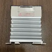 G3PE-515B unit removed from the box, showing the built-in heat-sink fins, DC12-24V input terminals, and 3-phase output terminals