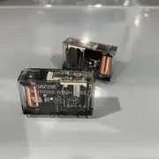 Omron G7SA-2A2B DC24 safety relay — two transparent G7SA relays with copper coils visible through the clear housing, showing G7SA-2A2B 24VDC markings and the PCB pin terminals on the bottom