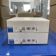 Omron G9SB-200-B AC-DC24V safety relay — two stacked white Omron retail boxes on blue surface showing Omron label TYPE G9SB-200-B, Chinese safety relay marking, VOLTS AC/DC24V, QTY 1, LOT 13925M, OMRON Corporation, MADE IN CHINA, CE and UKCA marks