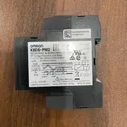 Omron K8DS-PM2 — side view showing the slim 17.5 mm body, the DIN-rail latch on the back, and the wiring layout with the three-phase input terminals on the bottom face