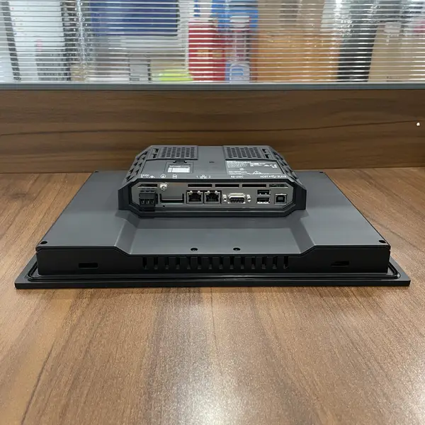 Omron NA5-12W101B-V1 HMI — rear view of the unit on a wooden surface showing the dual Ethernet ports, two USB host ports, USB slave port, RS-232C port, 24 VDC power terminal block, and SD card slot