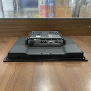 Omron NA5-12W101B-V1 HMI — rear view of the unit on a wooden surface showing the dual Ethernet ports, two USB host ports, USB slave port, RS-232C port, 24 VDC power terminal block, and SD card slot