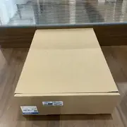 Omron NA5-12W101B-V1 HMI — brown cardboard shipping box on a wooden surface with Omron label TYPE NA5-12W101B-V1, QTY 1, OMRON Corporation, MADE IN CHINA