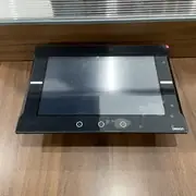 Omron NA5-12W101B-V1 HMI — front view of the actual 12.1-inch touchscreen showing the widescreen display with multi-touch overlay, black bezel with OMRON logo at bottom right, and indicator LEDs