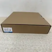 Omron NB10W-TW01B HMI — brown cardboard shipping box on the floor with Omron label TYPE NB10W-TW01B VER 1.1, LOT 05924M, QTY 1, OMRON Corporation, MADE IN CHINA, and Chinese-language shipping markings