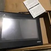 Omron NB7W-TW00B — open brown cardboard outer sleeve showing the inner brown product box with the NB7W-TW00B / PROGRAMMABLE TERMINAL label, Ver. 1.1, KCC-REM-OMR-NC-00483 KC mark, lot number, barcode, and blue-and-white OMRON band