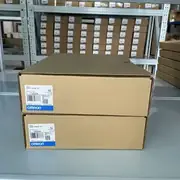 Omron NS8-TV01-V2 NS-series HMI — two stacked retail boxes on warehouse shelving showing Omron type labels TYPE NS8-TV01B-V2 (bezel variant sibling), LOT 13522K / 29622K, OMRON Corporation, Made in Japan, QTY 1