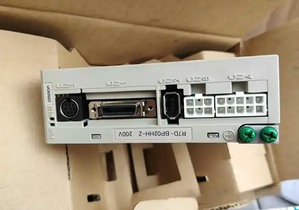Omron R7D-BP02HH-Z — front face of the SmartStep 2 drive with OMRON wordmark, mini-DIN encoder CN1, DB-15 I/O CN2, mini-USB CN3, and the CN3A / CN3B / CN4 white terminal blocks plus green PE ground screw, sitting on its cardboard tray