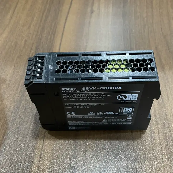 Omron S8VK-G06024 60 W 24 VDC 2.5 A PSU - front view showing the slim 32 mm wide form factor, the input/output terminal blocks with finger-safe covers, the V.ADJ output voltage adjustment trimmer, and the green DC ON LED